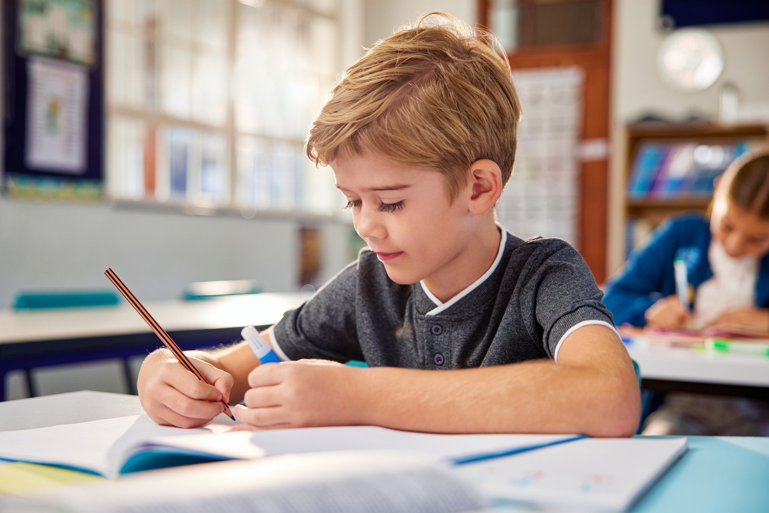 Child writing in notebook at primary school